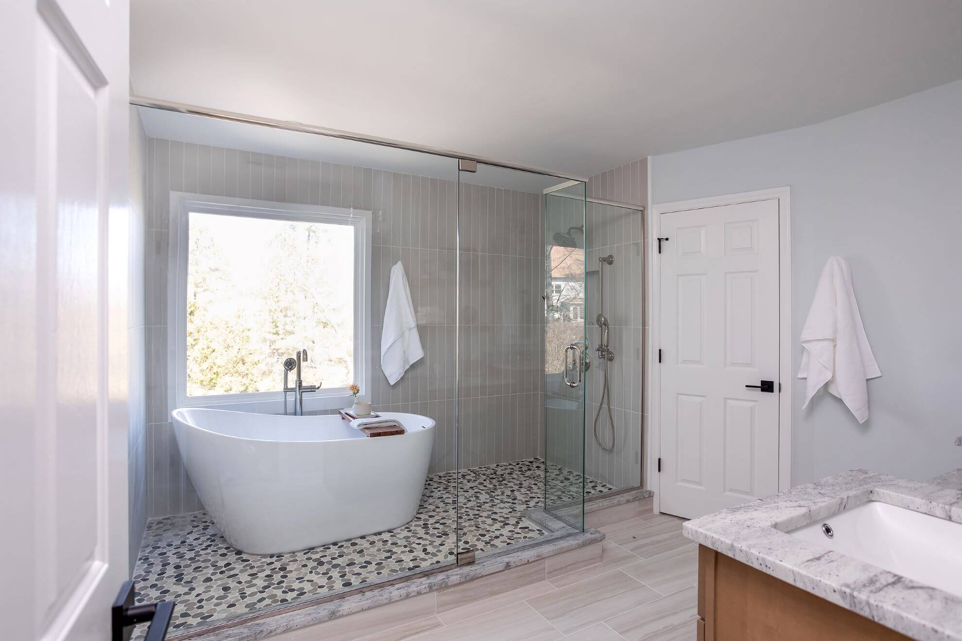 Full view Cary master bathroom renovation with freestanding tub, frameless glass shower, granite vanity, and gray subway tile walls