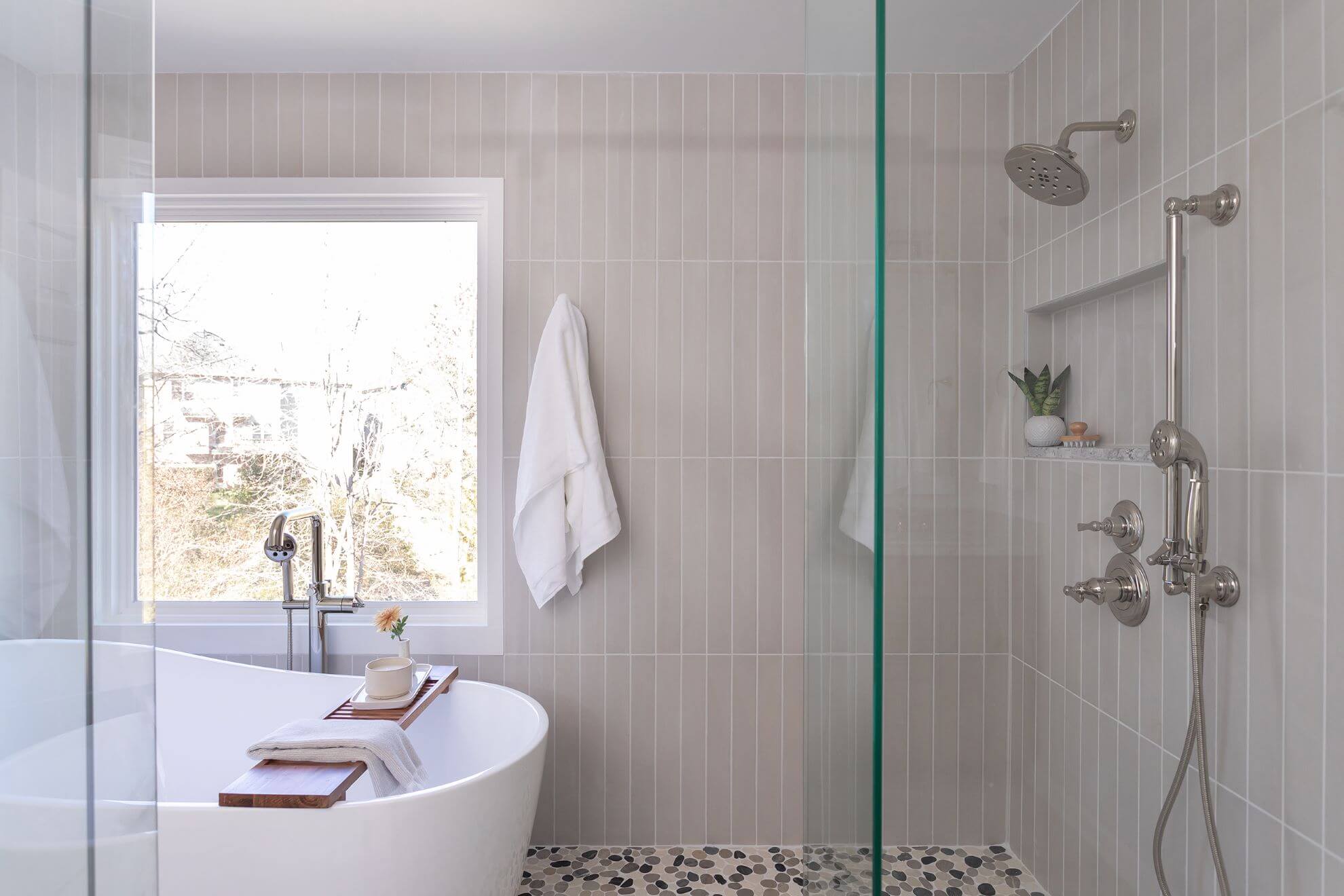 Cary NC spa bathroom remodel featuring freestanding soaking tub, vertical subway tile, pebble floor shower, and brushed nickel fixtures