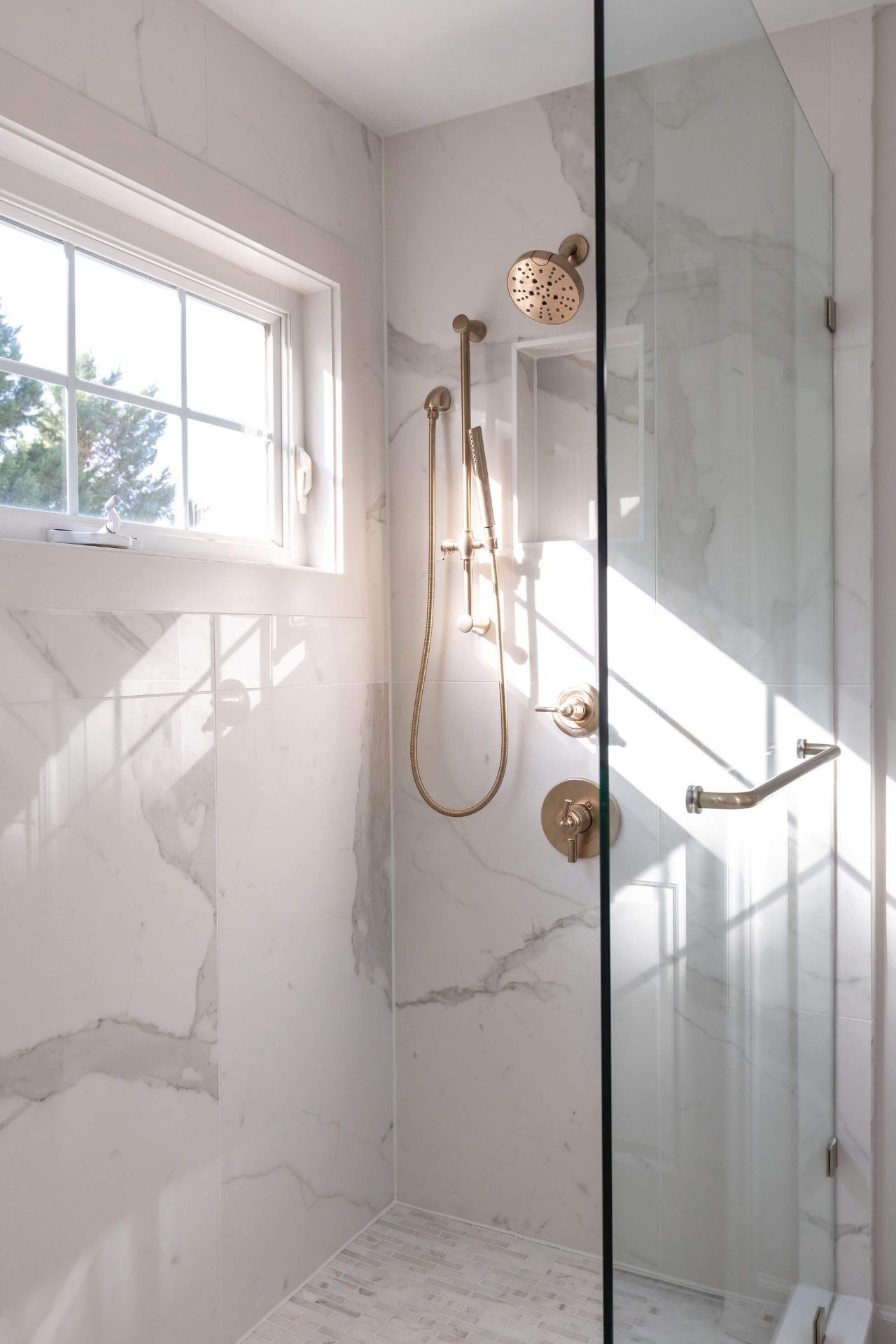 Morrisville walk-in shower with floor-to-ceiling Calacatta marble tile, champagne bronze fixtures, and frameless glass door