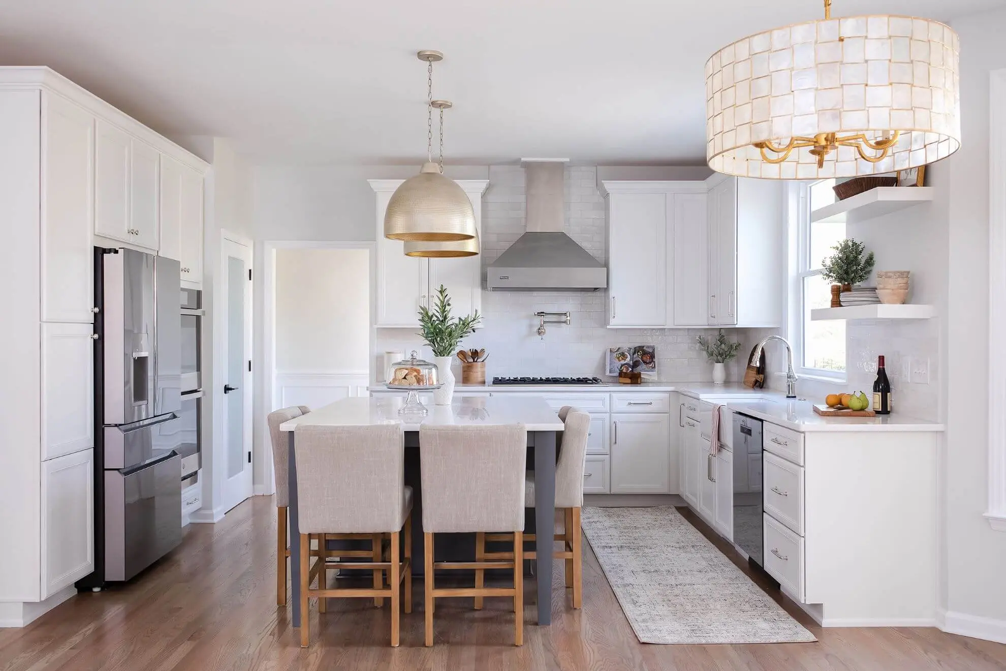 Luxury white kitchen remodel in Cary NC featuring custom cabinetry, quartz island with seating, and brass pendant lighting by Butler Homes