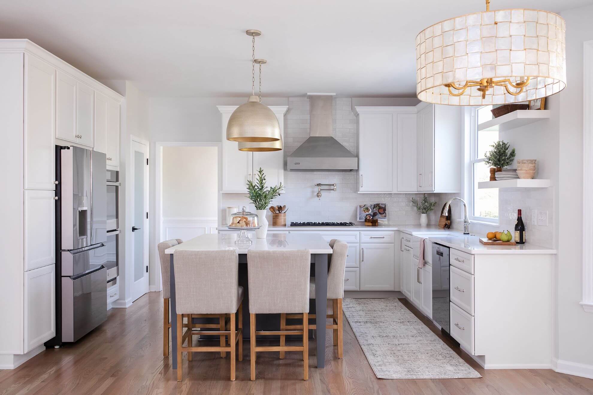 Luxury white kitchen remodel in Cary NC featuring custom cabinetry, quartz island with seating, and brass pendant lighting by Butler Homes