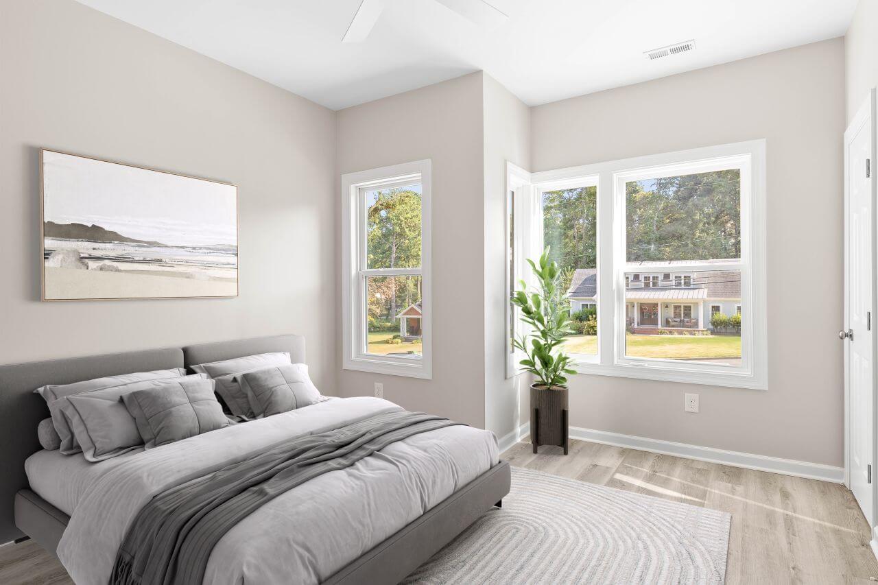 Fuquay-Varina duplex master bedroom with warm taupe walls, platform bed, gray bedding, corner windows, LVP flooring, ceiling fan, and landscape artwork