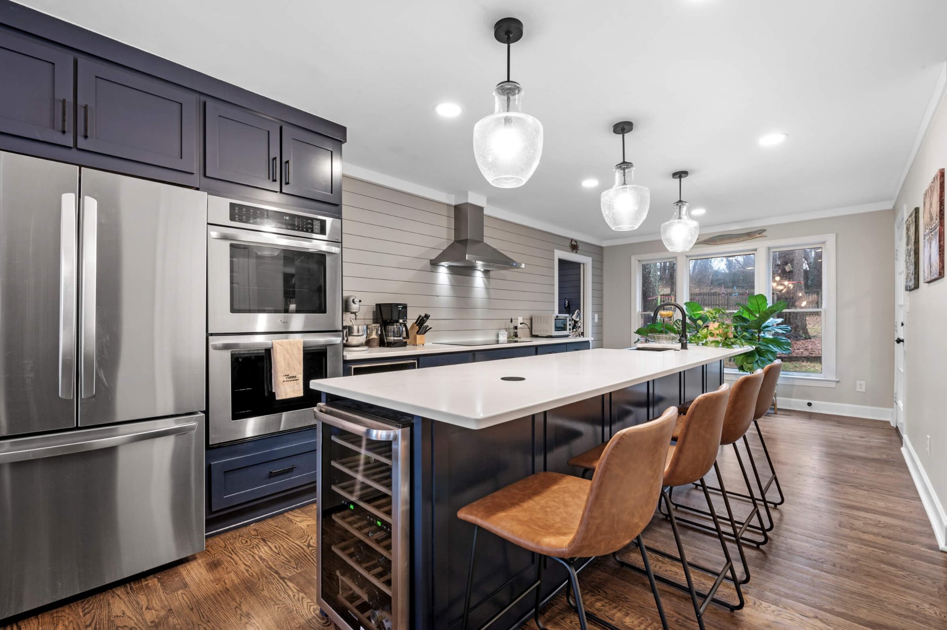 Modern kitchen remodel in Apex NC featuring navy blue cabinets with white quartz island and pendant lighting