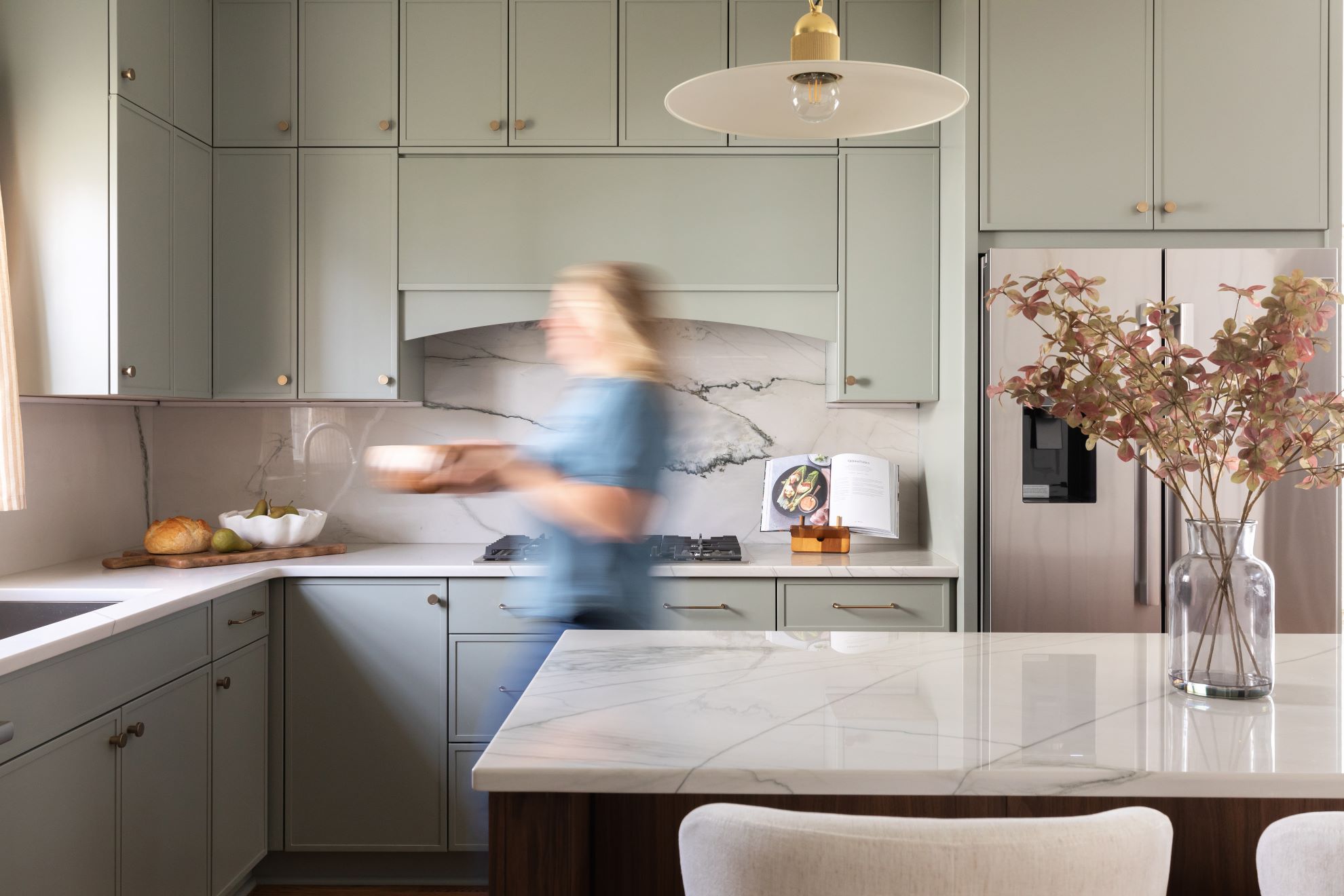 Cary NC kitchen remodel featuring sage green cabinets with marble backsplash, white quartz island, and brass pendant lighting