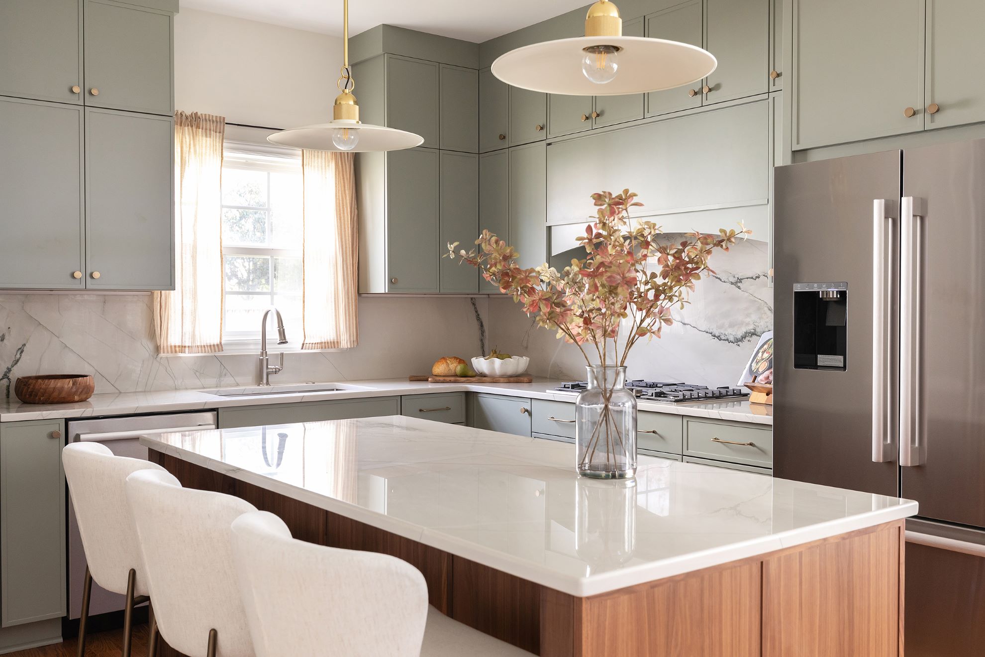 Modern Cary NC kitchen with sage green shaker cabinets, walnut island base, white marble countertops, and brass pendant lights