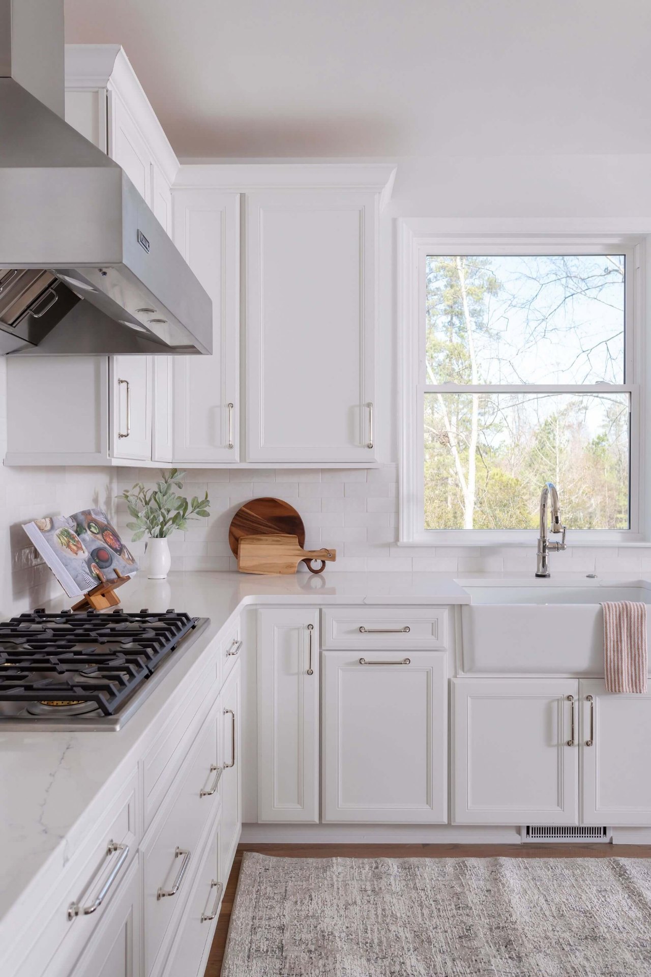 Bright white kitchen with farmhouse apron sink, custom cabinetry, and natural light from garden window