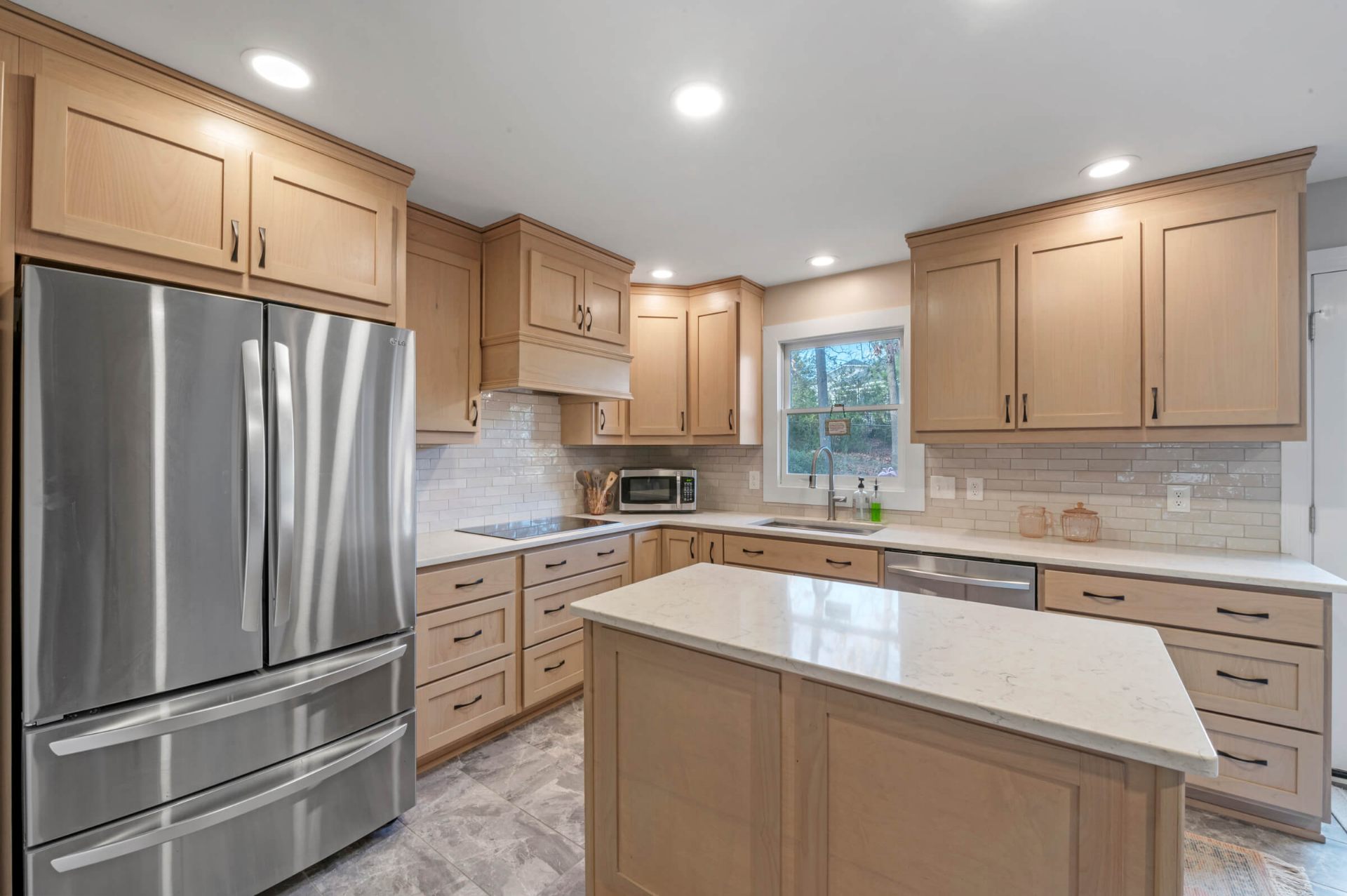 Fuquay-Varina kitchen island view showcasing white quartz countertops, French door refrigerator, and recessed lighting