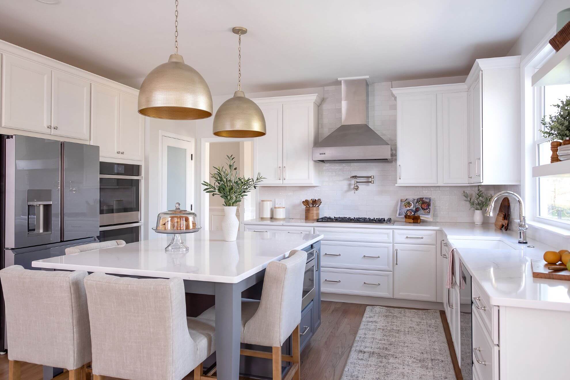 Full kitchen renovation with white shaker cabinets, blue island, stainless appliances, and gold pendant lighting