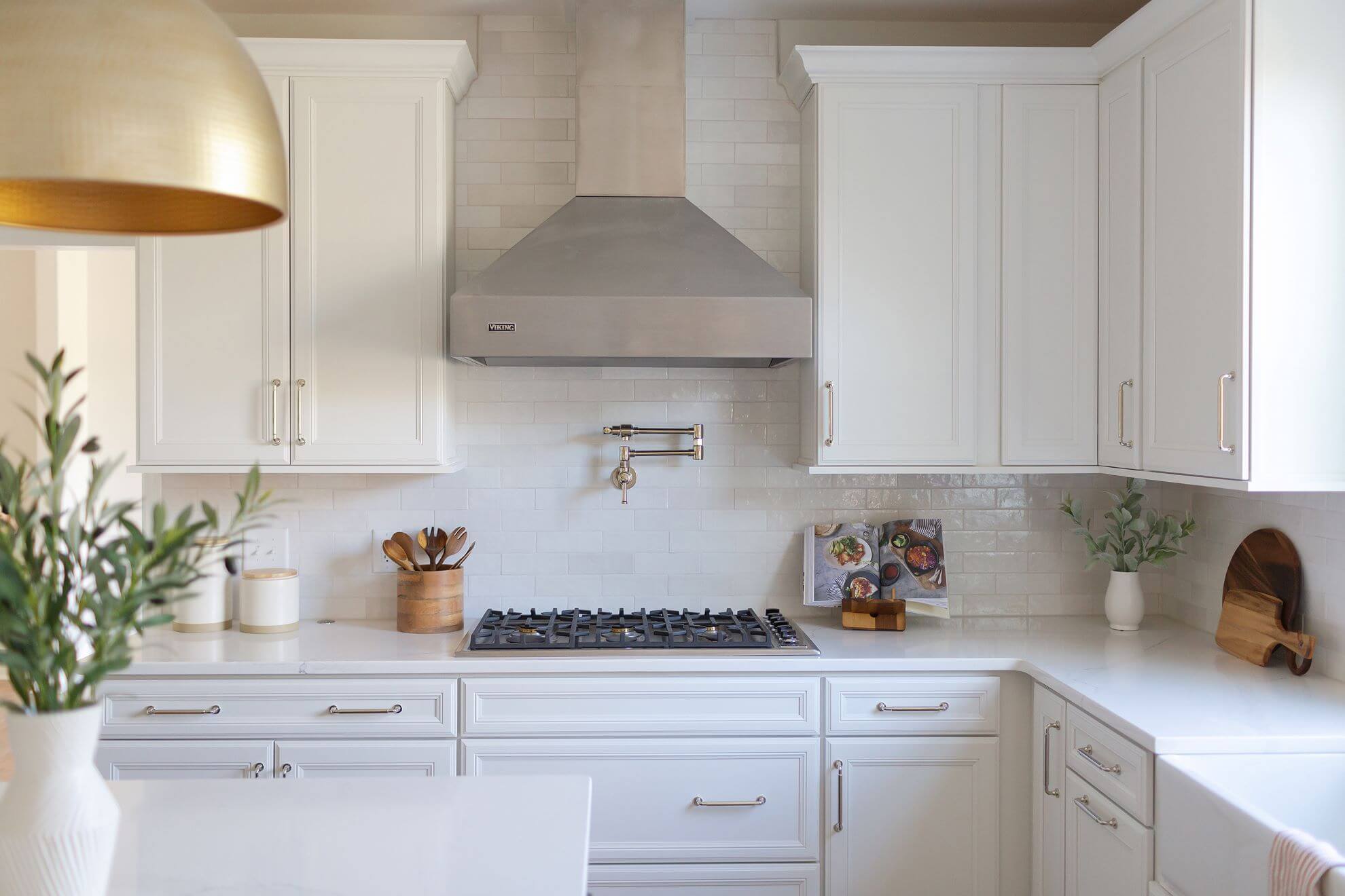 Gourmet kitchen cooking station with Viking gas range, pot filler faucet, and custom stainless steel hood