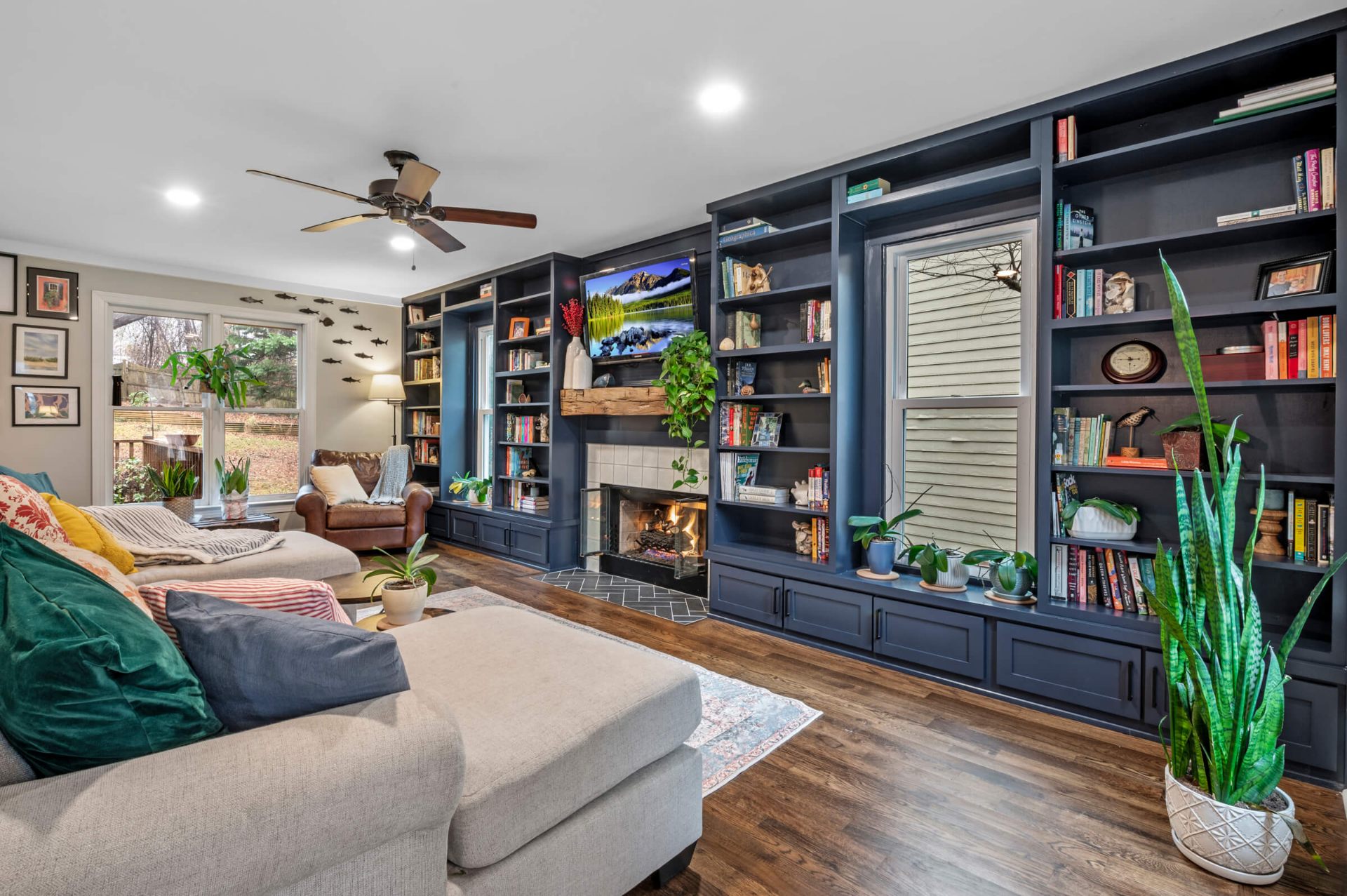 Apex NC living room remodel featuring navy blue custom built-in bookshelves, reclaimed wood fireplace mantel, and hardwood flooring