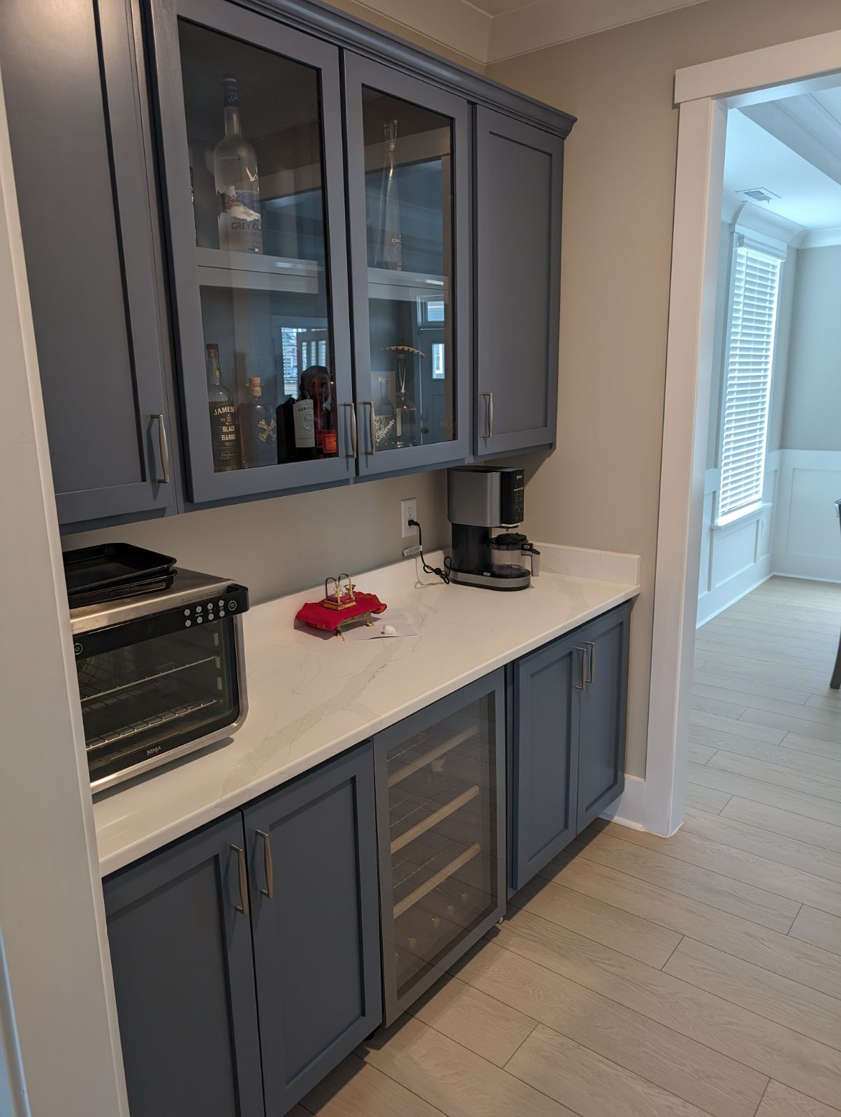 Butler pantry bar with blue-gray cabinets, glass-front upper cabinets, quartz countertops, and built-in wine cooler