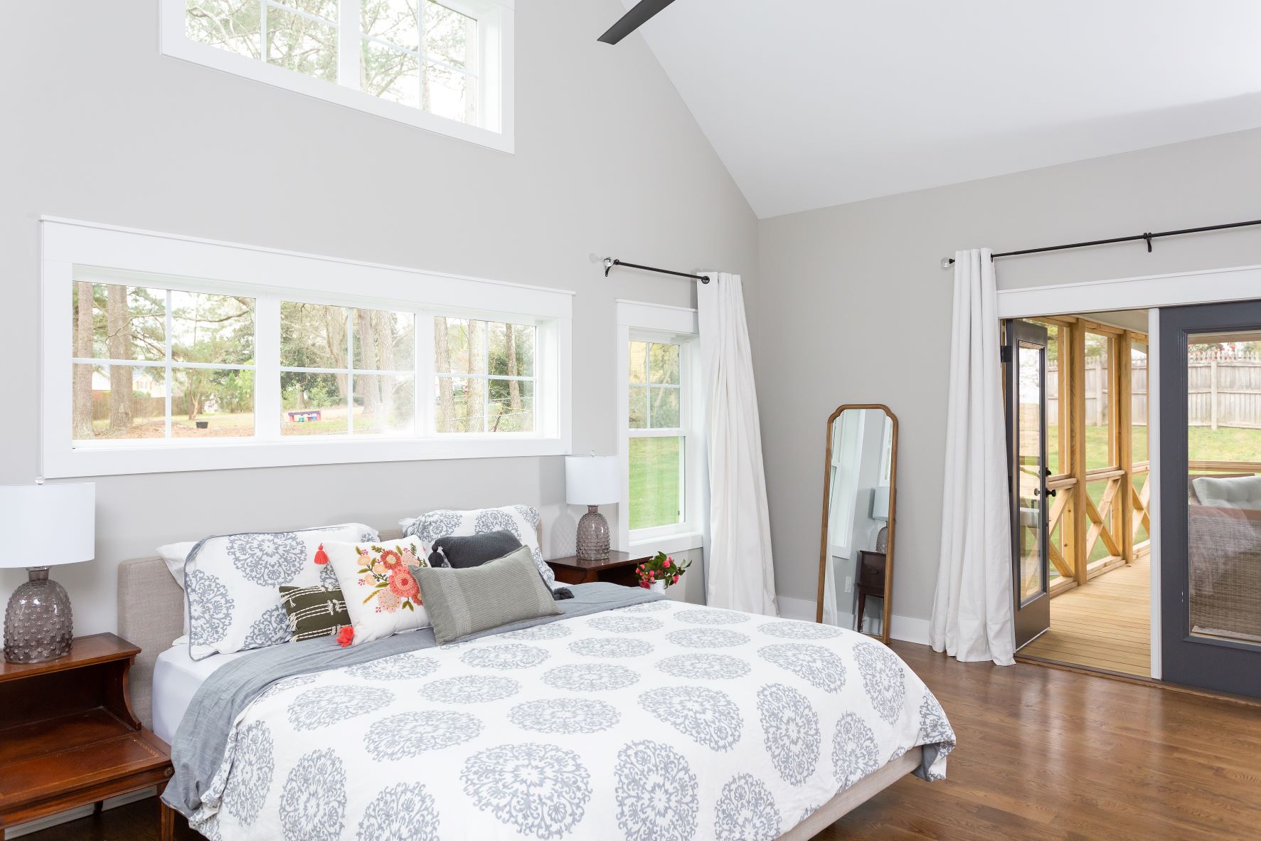 Fuquay-Varina master bedroom with vaulted ceiling, clerestory windows, French doors to screened porch, hardwood floors, and ceiling fan