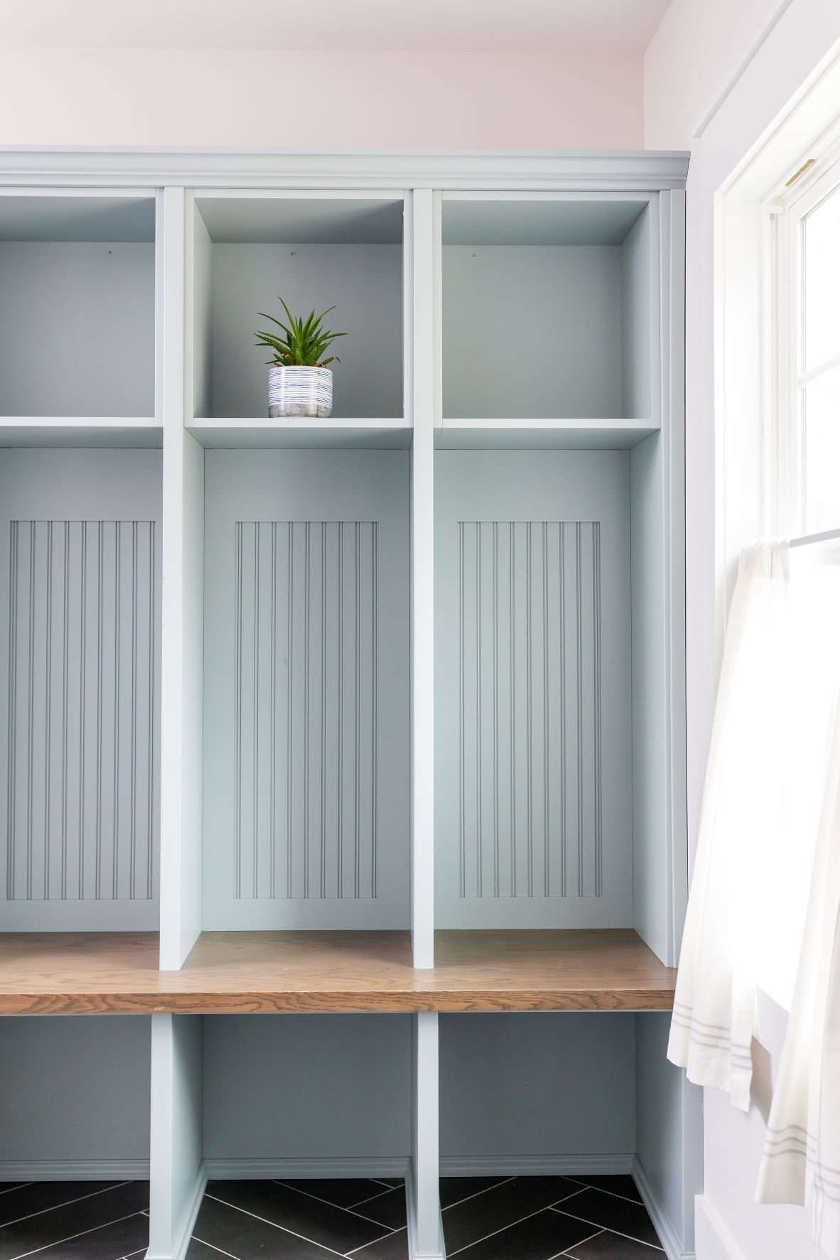 Fuquay-Varina mudroom with sage green painted built-in cubbies, beadboard backing, natural wood bench seat, and herringbone tile floor