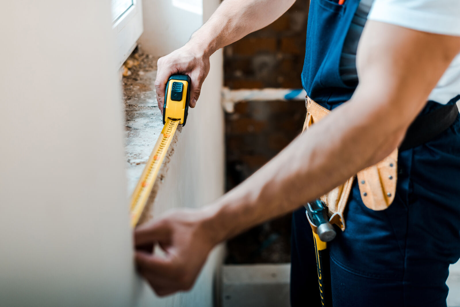handyman with measuring tape for window replacement