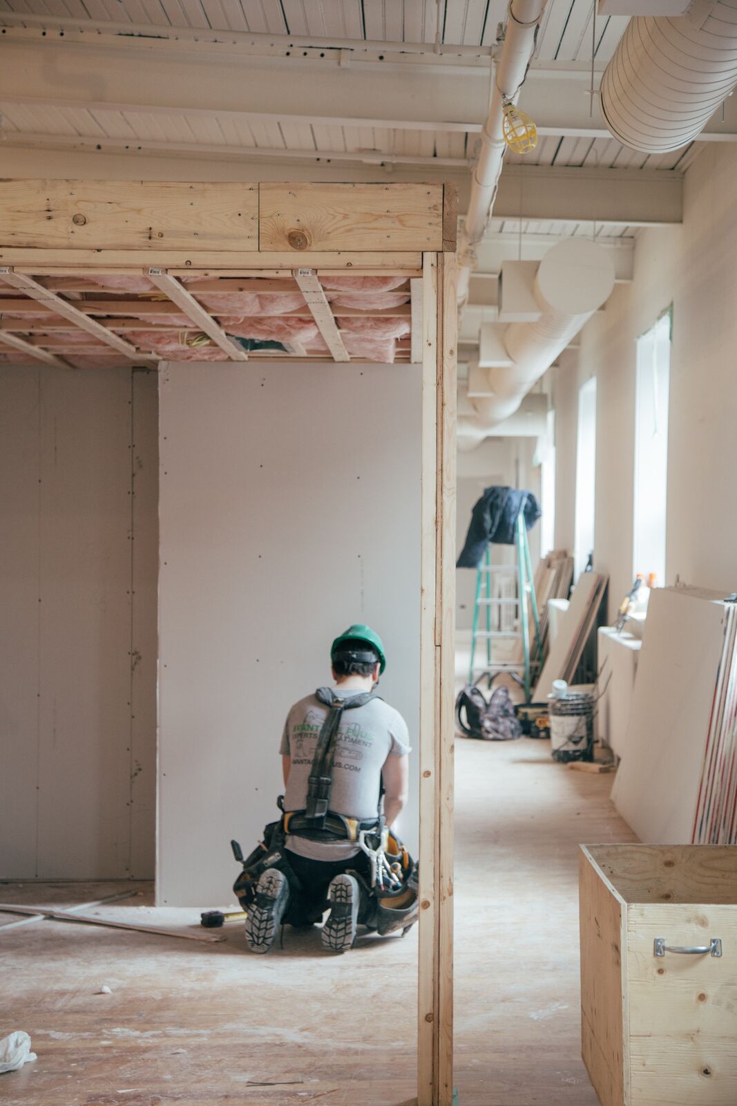 handyman working on home renovation with open studs and drywall panels