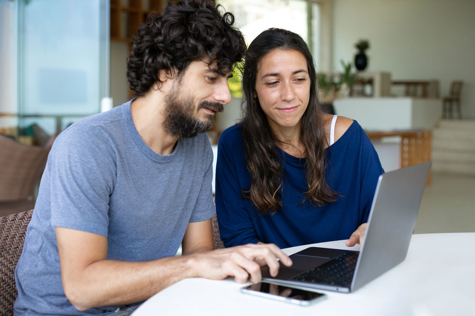 male female couple looking at laptop computer screen on white table